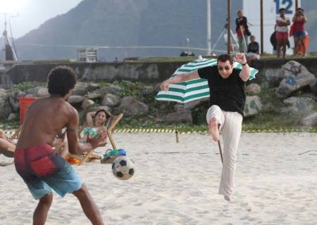 John Travolta joga futebol durante gravação em praia do Rio